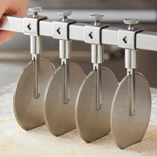 A hand holding a metal Ateco pastry cutter wheel.