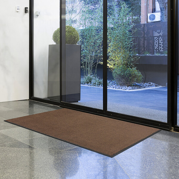A brown Lavex Olefin entrance mat on a floor.