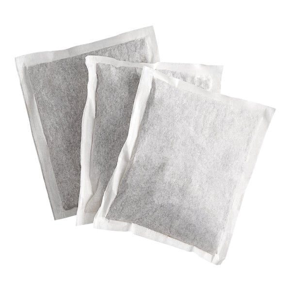 Three rectangular, white filter bags filled with a dark substance are overlapping each other on a white background.