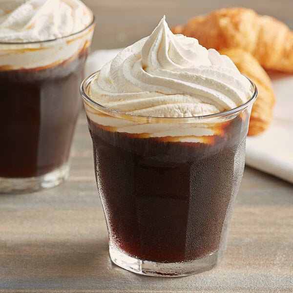 A glass of Caribou Coffee with whipped cream and croissants on a plate.