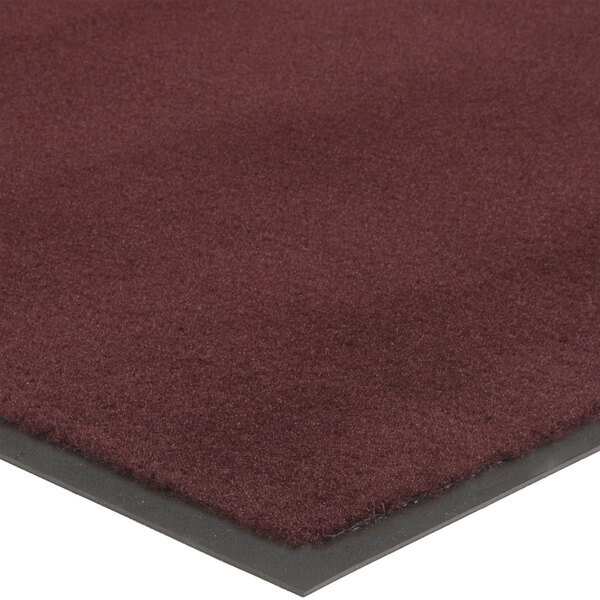 A close-up of a burgundy carpet mat with a black border.