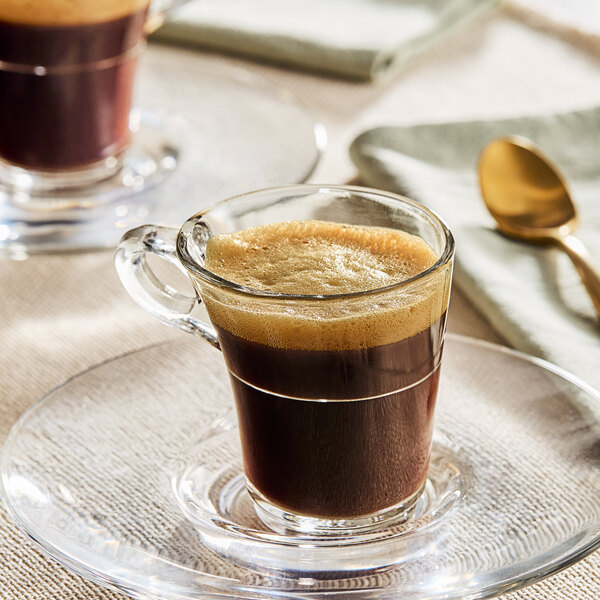 A saucer with a glass of Caribou Coffee espresso and a spoon.