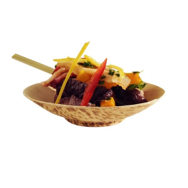 A Solia bamboo leaf bowl filled with food on a table.