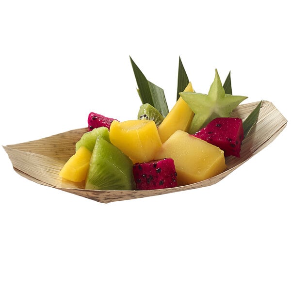 A Solia bamboo leaf boat dish filled with tropical fruit on a table in a salad bar.