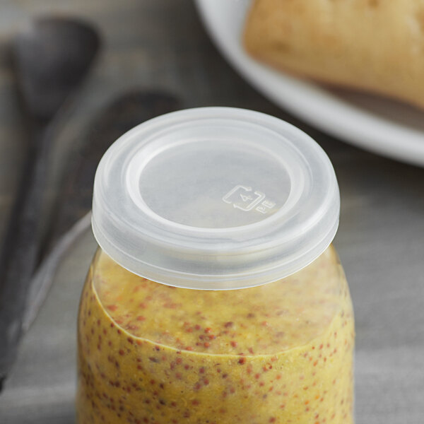 An American Metalcraft plastic jar lid on a jar of yellow liquid on a table.