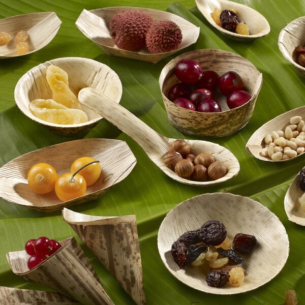A group of Solia bamboo leaf bowls filled with a variety of fruits and nuts on a table.
