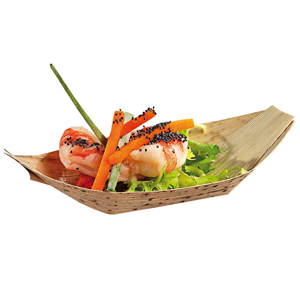 A Solia bamboo leaf boat dish filled with shrimp, carrots, and lettuce on a table.