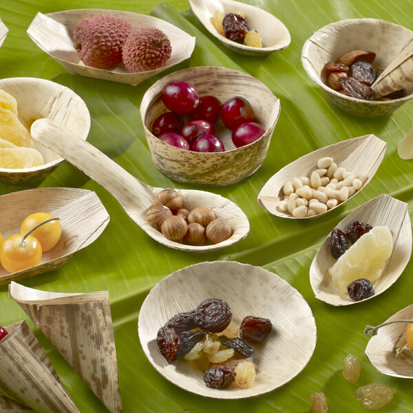 A table with bowls of fruit and nuts, including lychee, dried fruit, and red berries, with wooden spoons.
