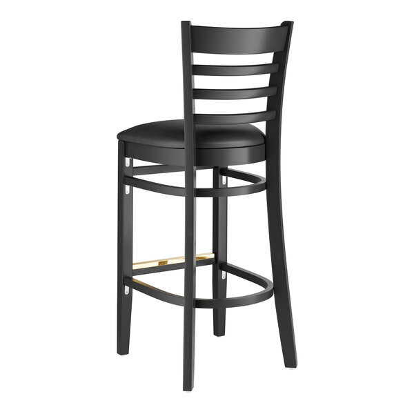 A Lancaster Table & Seating black wood ladder back bar stool with black vinyl seat.