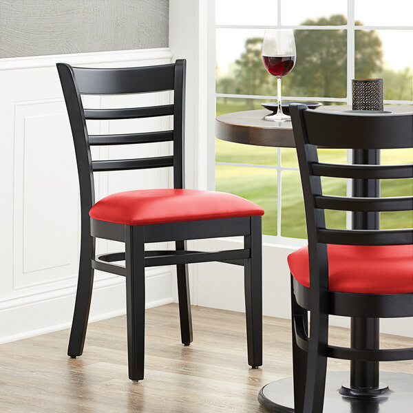 A Lancaster Table & Seating black wood chair with a red vinyl seat