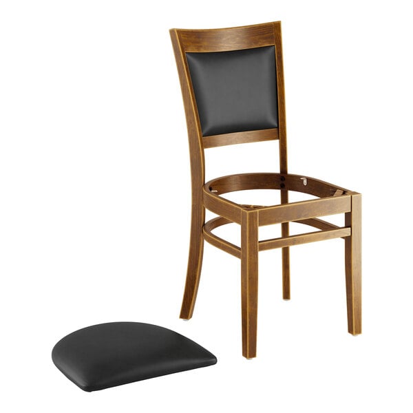 A Lancaster Table & Seating Sofia wood chair with black vinyl cushion on the seat.