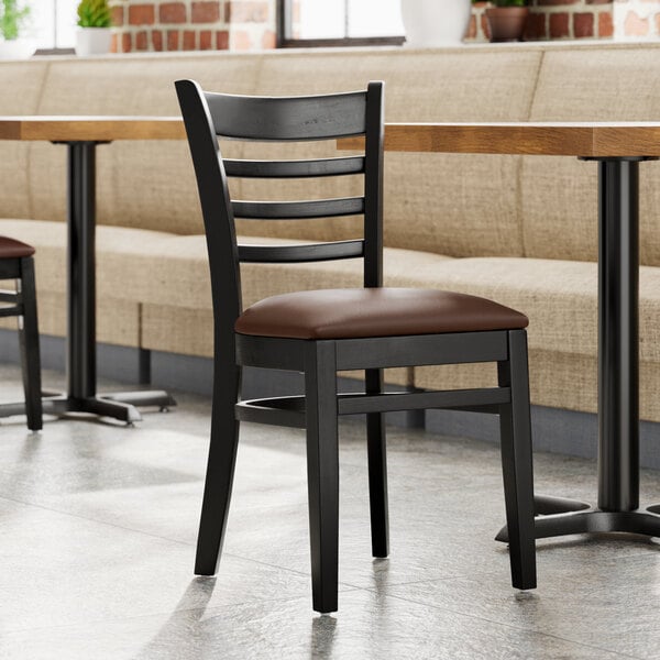 A Lancaster Table & Seating wood ladder back chair with a dark brown vinyl seat.