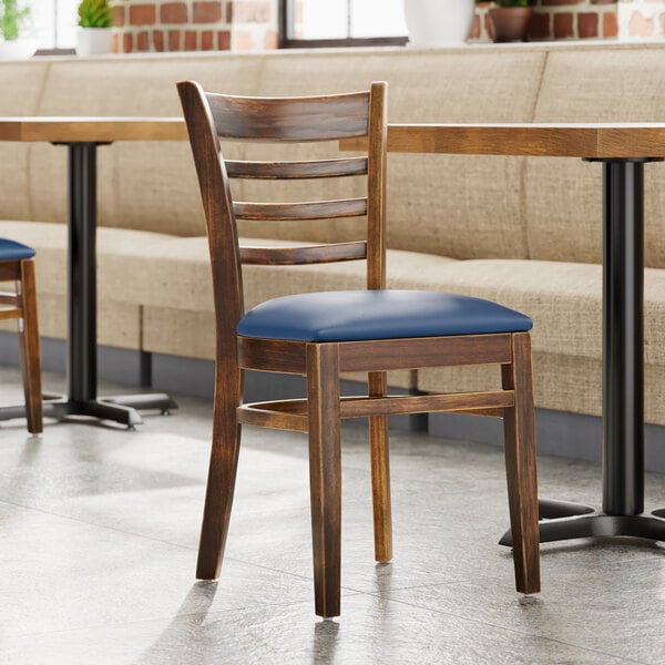A Lancaster Table & Seating wooden ladder back chair with a detached blue vinyl seat