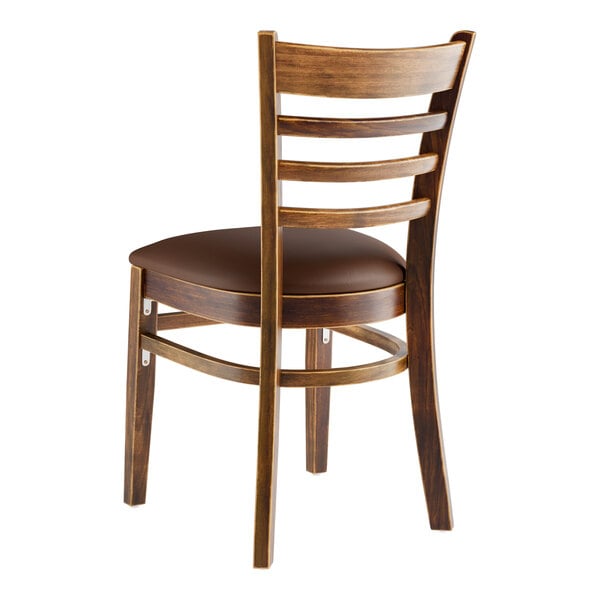 A Lancaster Table & Seating wooden ladder back chair with dark brown vinyl seat.