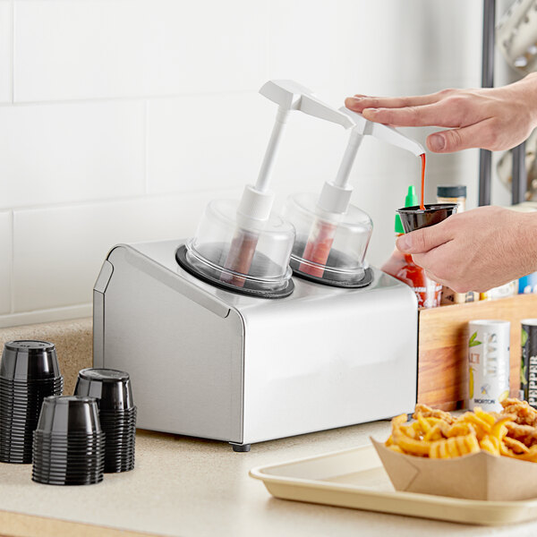 A person pouring red sauce into a Steril-Sil condiment dispenser.