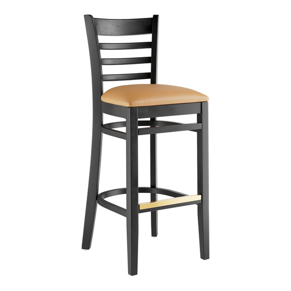 A Lancaster Table & Seating black wood bar stool with a light brown vinyl seat and ladder back.