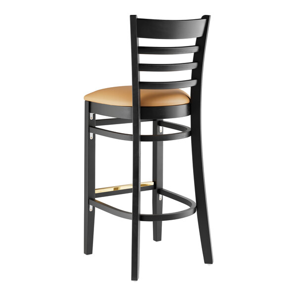 A Lancaster Table & Seating black wood bar stool with light brown vinyl seat.