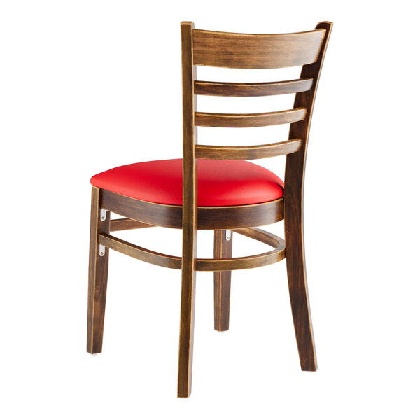A Lancaster Table & Seating wooden ladder back chair with a red vinyl seat.