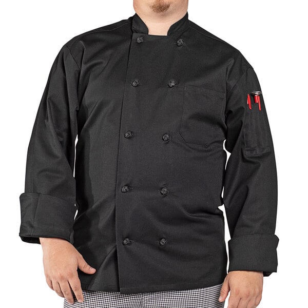 A man wearing a black Uncommon Chef long sleeve chef coat standing in a professional kitchen.