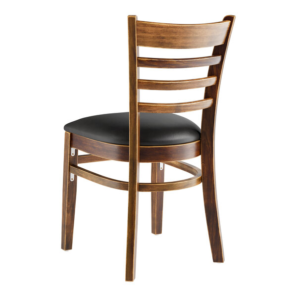 A Lancaster Table & Seating wooden ladder back chair with a black vinyl cushion.