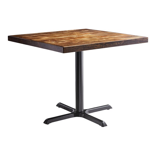 A Lancaster Table & Seating square wooden table with a black cast iron base.