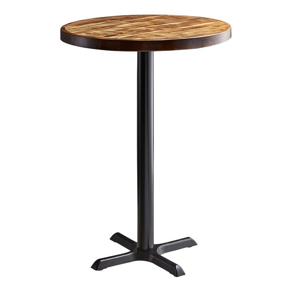 A Lancaster Table & Seating round wooden table with a black cast iron base.
