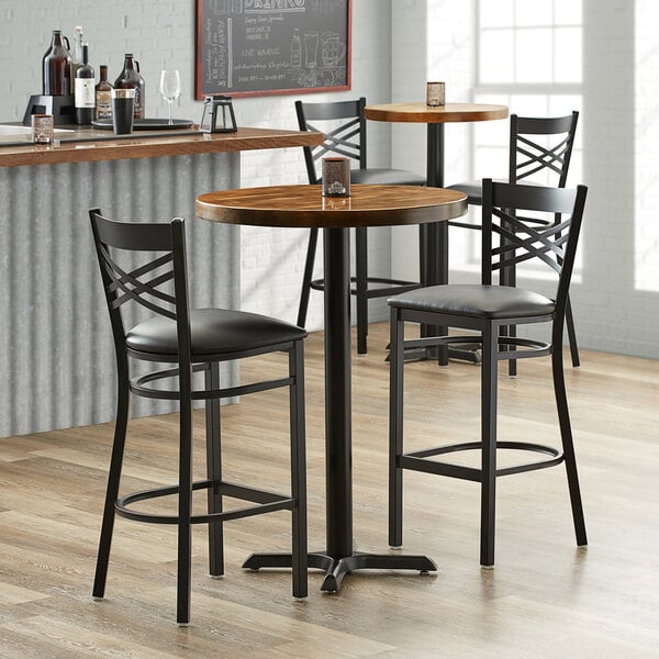 A Lancaster Table & Seating round butcher block table with a cast iron base plate in a cocktail bar.