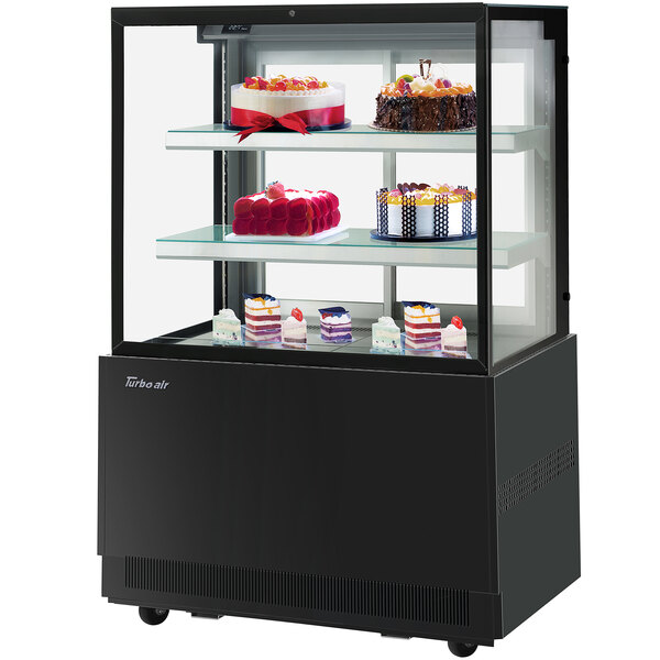 A Turbo-Air black refrigerated bakery display case with cakes on it.