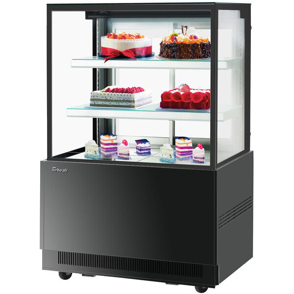 A Turbo-Air black refrigerated bakery display case with cakes on it.