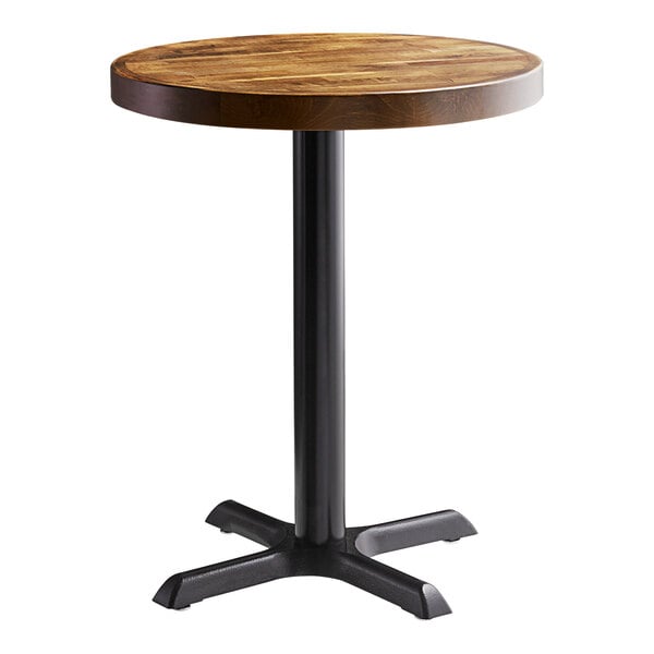 A Lancaster Table & Seating round wooden table with a cast iron base plate.