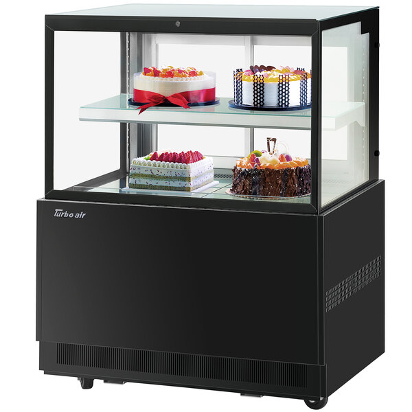 A Turbo-Air black refrigerated bakery display case with cakes on it.