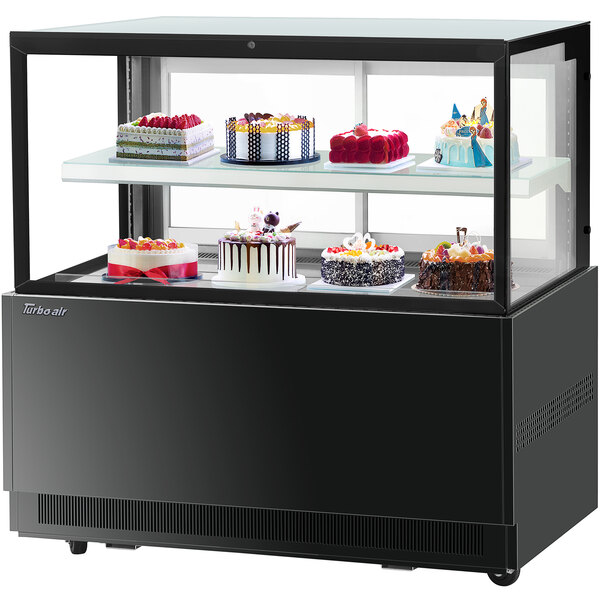 A Turbo-Air black refrigerated bakery display case with cakes on two tiers.