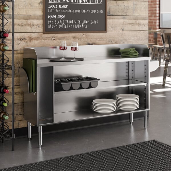 A 60-inch stainless steel bussing or waitress station with a pan holder, featuring shelves for storage and a side towel rack.