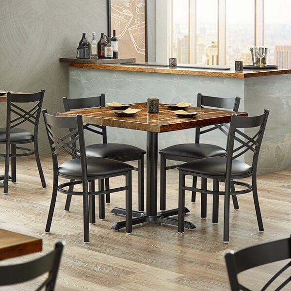 A Lancaster Table & Seating vintage wood table with black chairs in a restaurant.