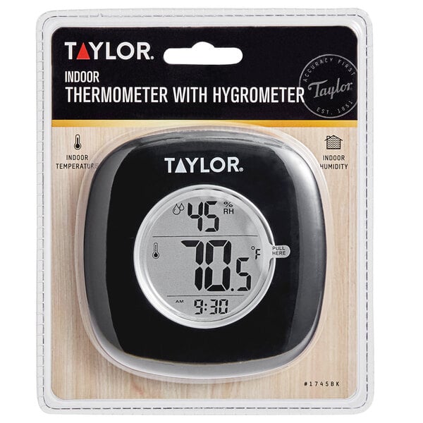 A black Taylor digital indoor thermometer and hygrometer on a wood surface.