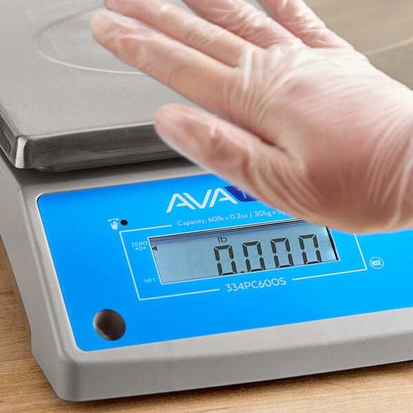 A person wearing a clear glove using an AvaWeigh digital portion control scale.