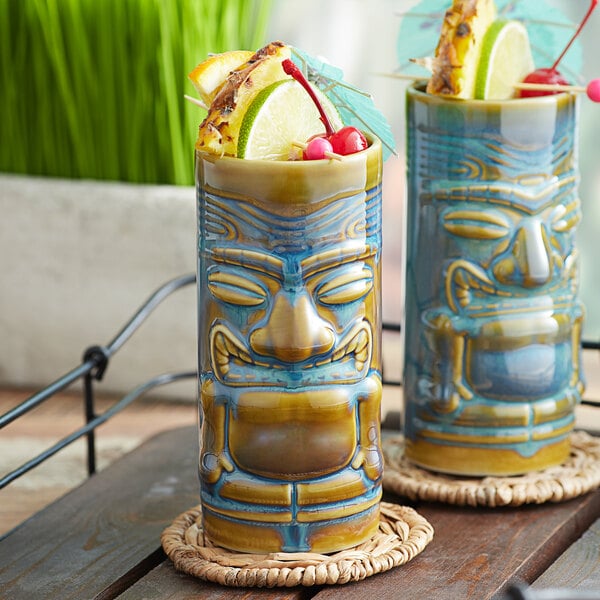 A pair of Tuxton ceramic tiki mugs with peacock designs.