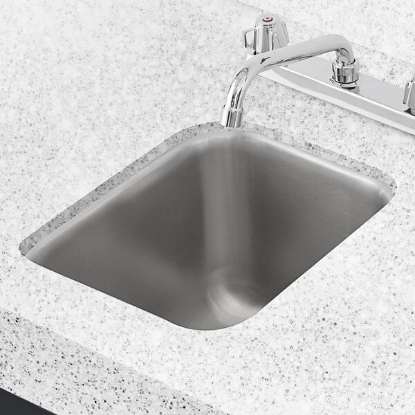 A Regency stainless steel undermount sink in a counter with a faucet.