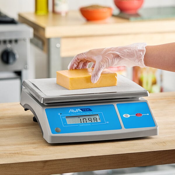 A digital portion control scale with an oversized platform and a block of cheese being weighed.