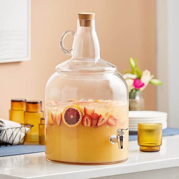 An Acopa glass beverage dispenser filled with fruit juice and fruit.