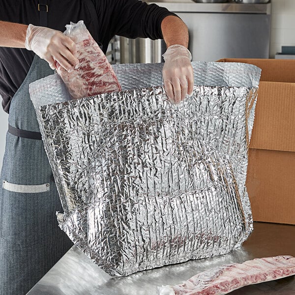 A person holding a Lavex insulated box liner with a piece of meat inside.