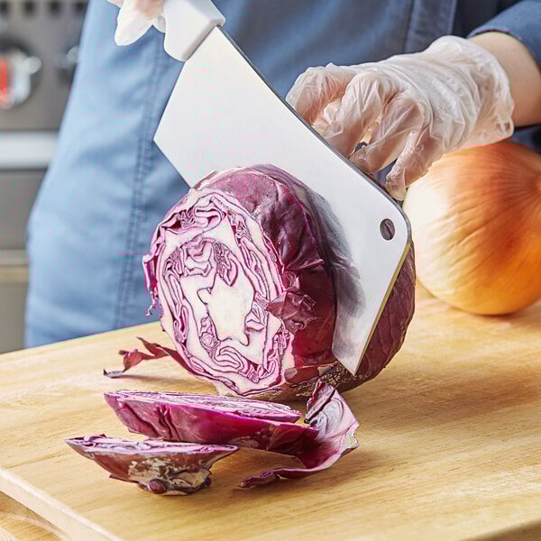 A person using a Choice stainless steel cleaver to cut a red cabbage.