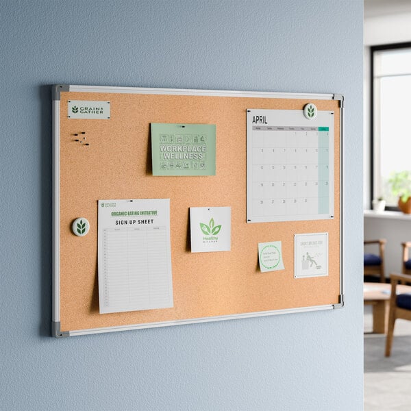 A rectangular wall-mounted cork board with an aluminum frame, displaying various papers and notes.