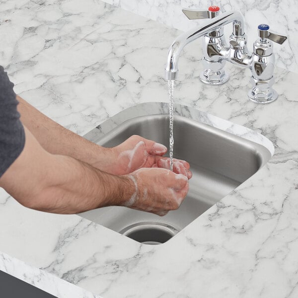 A person washing their hands in a Waterloo stainless steel undermount sink.