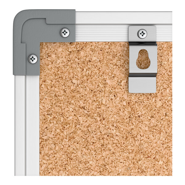 A wall-mount cork board with an aluminum frame and mounting hardware visible in the corner.