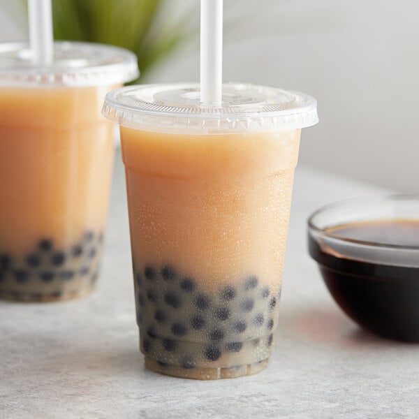 A couple of plastic cups with brown Bossen Wintermelon drinks and black balls.