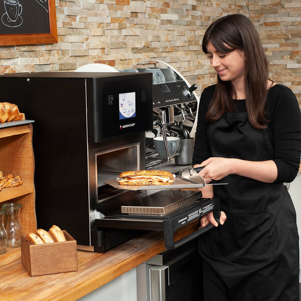 A Merrychef eikon e1s Classic High-Speed Accelerated Cooking Countertop Oven being used to heat a sandwich in a commercial kitchen setting.