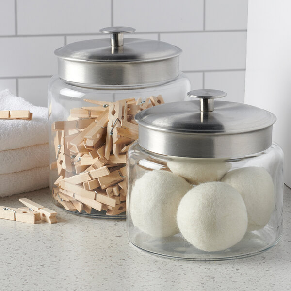 A clear glass jar with a brushed metal lid, shown storing household items.