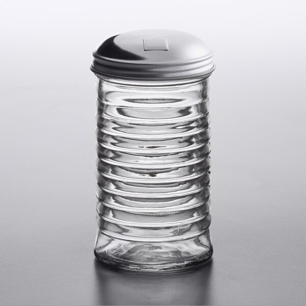 An American Metalcraft glass beehive sugar pourer with a stainless steel lid on a table.