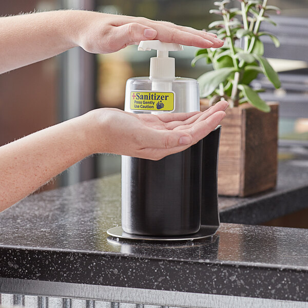 A person using a Steril-Sil black hand sanitizer dispenser.